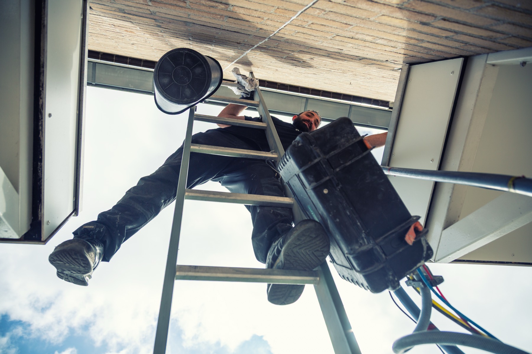 Monteur op de ladder tijdens het isoleren, van onderaf gefotografeerd