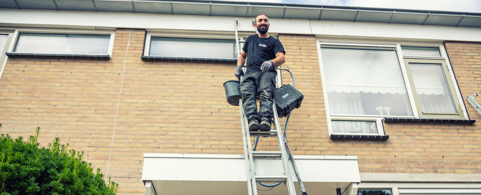 Monteur op de ladder brengt InsuCore isolatieschuim aan in de spouwmuur van een woning in Barendrecht